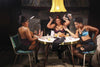 Three modern Black pin-up models in lingerie play cards around a table, laughing as one tosses cards in the air. Drinks and scattered cards set a lively vibe in "Chocolate Cheesecake 2" from Schiffer Publishing, Ltd.