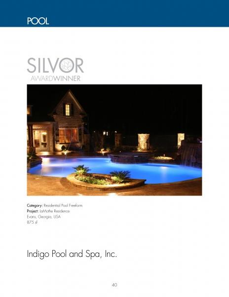 A glowing, uniquely shaped backyard pool with blue lighting and elegant landscaping surrounds a stone house. Text reads “SILVER AWARD WINNER.” Below: International Award-winning Pools by Schiffer Publishing, Ltd.—showcasing excellence.