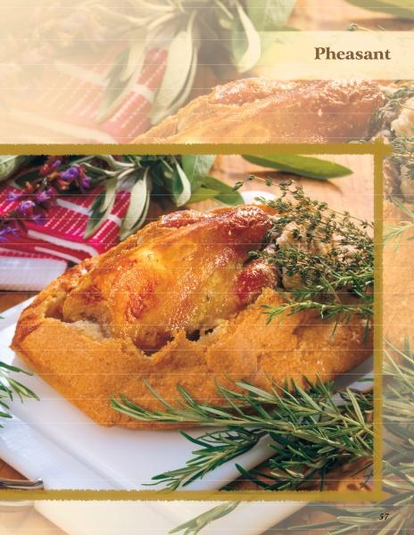 A golden-brown pheasant pie from "Cooking Wild Game" by Schiffer Publishing, Ltd. rests on a white cutting board, garnished with thyme and rosemary, with a red-and-white towel and leafy herbs in the background.