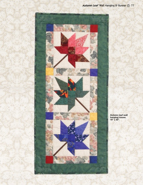 The "Quilts of Chestnut Ridge" by Schiffer Publishing, Ltd. is a rectangular quilted wall hanging or runner with three patchwork maple leaves in red, green, and blue on a light background and green border—great for autumn décor.