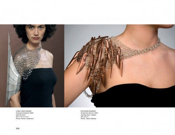 A woman models "On Body and Soul" jewelry by Schiffer Publishing, Ltd.: a metallic, wing-like shoulder armor on her right and a spiked metal with chain design on her left, both paired with a black strapless top.