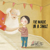 An elderly man with a white beard gently lifts a smiling child in a red-striped shirt against a backdrop of pink pennant flags, evoking the uplifting children’s book The Magic in a Smile by Schiffer Publishing, Ltd. about emotional management.