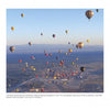 Dozens of colorful hot-air balloons soar above Albuquerque, with mountains and town below, as featured in "Balloons Over Albuquerque" by Schiffer Publishing, Ltd., highlighting the record 2011 Balloon Fiesta launch.