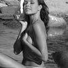 In "Paradise in Brazil" by Schiffer Publishing, Ltd., a Brazilian woman relaxes in shallow water, eyes closed, holding a large seashell to her face as rocky shorelines in the background evoke lush tropical scenery.