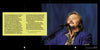 A long-haired, mustached man in a blue patterned jacket sings with eyes closed, breaking biker stereotypes. To the left, yellow text on black highlights "The Meaning of Life According to Bikers" by Schiffer Publishing, Ltd.