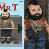 I Pity the Dolls" by Schiffer Publishing, Ltd. is a soft sculpture folk art doll inspired by Mr. T—standing upright with a mohawk, overalls, sneakers, gold chains, and barbell—crafted after a Martha Holcombe pattern for collectors and fans.