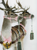 Two deer with pink bows, gold heart ornaments, and green tasseled reins stand against a white background—an image featured in "Humor in Craft" by Schiffer Publishing, Ltd., celebrating the playful spirit of contemporary craft artists.
