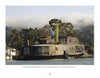 A large, rustic floating home featured in "Houseboats" by Schiffer Publishing, Ltd. showcases weathered wood siding on a river amid trees and misty hills, capturing the timeless charm of classic houseboat architecture.