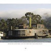 A large, rustic floating home featured in "Houseboats" by Schiffer Publishing, Ltd. showcases weathered wood siding on a river amid trees and misty hills, capturing the timeless charm of classic houseboat architecture.