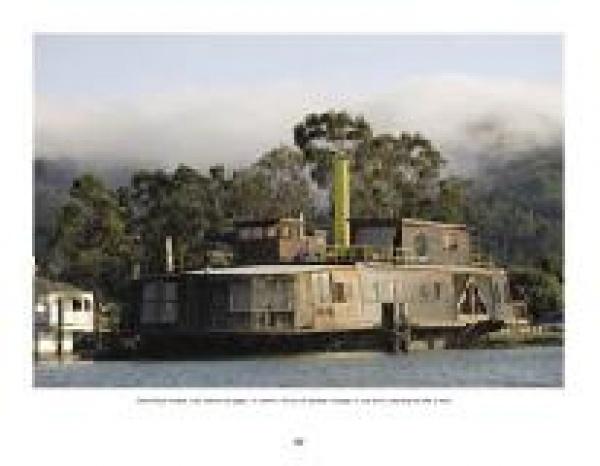 A large, rustic floating home featured in "Houseboats" by Schiffer Publishing, Ltd. showcases weathered wood siding on a river amid trees and misty hills, capturing the timeless charm of classic houseboat architecture.