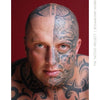 A bald man with intricate black tattoos on his face and upper body stares at the camera, set against a deep red background. Featured in "The Tattoo Project" by Schiffer Publishing, Ltd., this portrait showcases bold tattoo artistry.