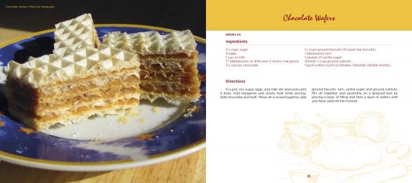 A slice of layered chocolate wafer cake sits on a blue and gold plate beside “Serbian Cooking” by Schiffer Publishing, Ltd.—a homage to traditional Serbian recipes and classic Eastern European desserts.