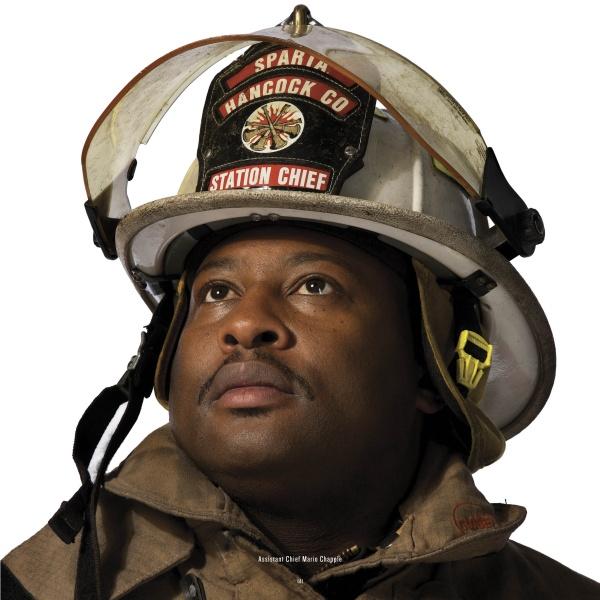 A firefighter in full gear and a white Sparta Hancock Co Station Chief helmet looks upward. This striking image, from "Local Heroes" by Schiffer Publishing, Ltd., captures the dedication of volunteer firemen.