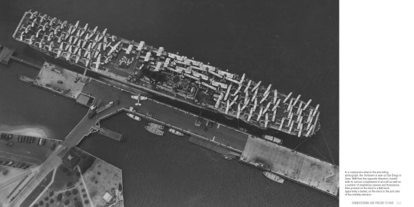 A black and white aerial photo from Schiffer Publishing, Ltd. features the USS Yorktown (CV-5), a renowned WWII aircraft carrier docked at a pier with airplanes on deck, surrounded by docks, water, shoreline, parked cars, and landscaping.