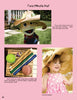 A page from Kinder Gardens by Schiffer Publishing, Ltd. shows instructions for a Two Minute Hat—great for kids’ outdoor fun. Photos feature a puppet, a girl in paper hats, and supplies like paper rolls, tape, and a ball in a basket.