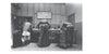 In "Grunts" by Schiffer Publishing, Ltd., four soldiers with duffel bags stand at a table while two men sit behind it, echoing classic U.S. Army draft scenes in photojournalistic essay style.