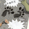 A storybook illustration from Shoes, Little Shoes, Big Shoes by Schiffer Publishing, Ltd. features green feet, animal paw prints, a mouse, and snapping hands, with comic-style "CLOMP CLOMP" and notes that narrate the book’s creative ending.