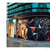 A street corner clothing store features a bold black geometric mural with white and red lines inspired by "Tape Art" from Schiffer Publishing, Ltd., creating a striking, angular look that catches the eyes of passing pedestrians.