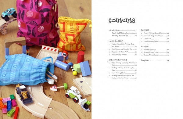 A colorful mix of fabric bags, wooden toy cars, and blocks are spread on a wooden floor. On the right, a contents page lists chapters for "Print It!" by Schiffer Publishing, Ltd., a kids crafts book with fun printmaking projects.