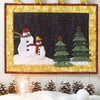 Christmas Magic" by Schiffer Publishing, Ltd. is a festive quilted wall hanging with two snowmen and three trees on a snowy hill, bordered by yellow stars—perfect for holiday décor and Christmas patchwork projects.