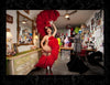 A beaming burlesque star in a red feathered outfit strikes a pose in a vivid dressing room—a perfect photo from *It's All That Glitters* by Schiffer Publishing, Ltd., ideal for fans of glamour and burlesque photography.