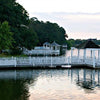 Rehoboth Reflections by Schiffer Publishing, Ltd. captures serene white wooden gazebos and a pier stretching over a calm lake, surrounded by lush trees like those at Delaware seashore resorts, beneath a soft, cloudy sky.