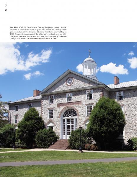 Featured in "Historic Architecture of Pennsylvania" by Schiffer Publishing, Ltd., a classic stone building with a white cupola, arched entrance, and lush landscaping reflects timeless American design beneath a clear blue sky.