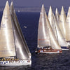 The book "Sailing Fascination" by Schiffer Publishing, Ltd. captures a stunning scene of sailing ships with tall white sails and yellow-clad crews racing closely on a calm blue sea, with a distant shoreline in the background.