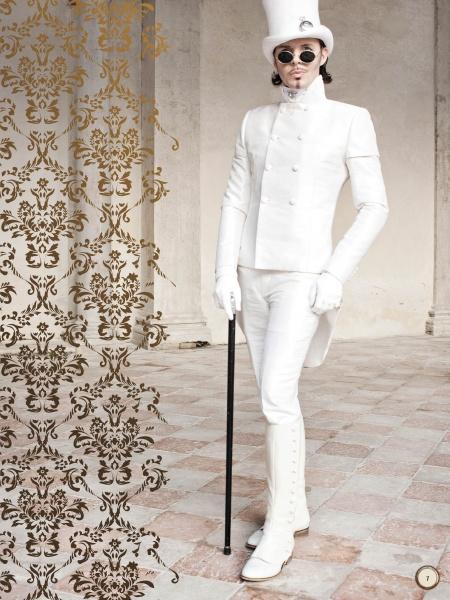 Dressed in white formalwear—top hat, gloves, boots—and accessorized with round sunglasses and a black cane, a model stands by a gold-patterned screen, showcasing International Steampunk Fashions from Schiffer Publishing, Ltd.