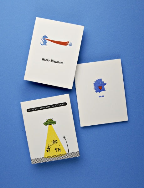 Today's Top Stationery Artists by Schiffer Publishing, Ltd. features three illustrated greeting cards: a dragon saying Happy Birthday, a hedgehog asking for a hug, and a UFO with animals wishing Happy extraterrestrial birthday.