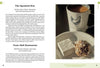 An open book, "Lancaster County Bucket List" by Schiffer Publishing, Ltd., shows a mug with a chicken logo, a marshmallow, and a pastry, highlighting must-visit Amish spots in Lancaster County.