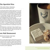 An open book, "Lancaster County Bucket List" by Schiffer Publishing, Ltd., shows a mug with a chicken logo, a marshmallow, and a pastry, highlighting must-visit Amish spots in Lancaster County.