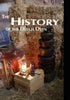A rustic scene displays Schiffer Publishing, Ltd.’s Dutch Oven: stacked cast-iron pots by straw bales, a crate with a lantern, mug, plate, and a brown saddle, with “The History of the Dutch Oven” text at the top.