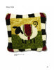 The "How to Hook Rugs" pillow by Schiffer Publishing, Ltd. showcases a white sheep with a black face and legs on a green and yellow background, accented with a black and white striped border and red corners.