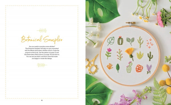 The book "Freshly Stitched" by Schiffer Publishing, Ltd. features a hand-embroidered botanical sampler in a hoop with green leaves, yellow and pink flowers, and gold scissors, perfect for fans of modern embroidery projects. Text reads "Botanical Sampler.