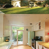 A mid-century modern house with a flat roof and large windows, inspired by "Modern Tract Homes of Los Angeles" from Schiffer Publishing, Ltd., is shown above a retro kitchen with white cabinets, green fridge, and dining area.