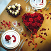The Seasonal Table Settings book by Schiffer Publishing, Ltd. inspires a romantic holiday table with gold linens, heart-shaped red and white roses, rose petals, and elegant plates with red rose centerpieces.