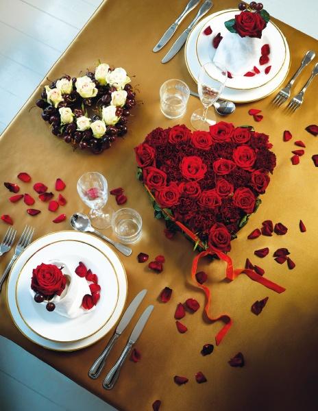 The Seasonal Table Settings book by Schiffer Publishing, Ltd. inspires a romantic holiday table with gold linens, heart-shaped red and white roses, rose petals, and elegant plates with red rose centerpieces.