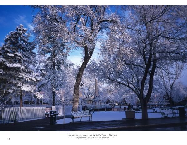 Experience the peaceful beauty of Santa Fe with "Santa Fe Reflections" by Schiffer Publishing, Ltd.—a scene of snow-covered benches, trees, and a historic plaza under a clear blue sky captures the charm of this iconic destination.