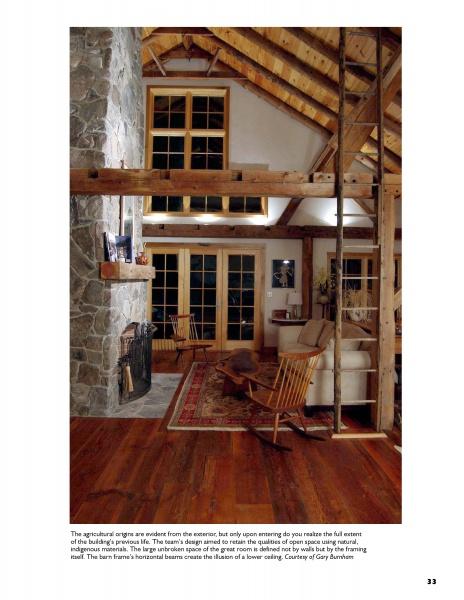 A cozy living room inspired by "Barn Again" from Schiffer Publishing, Ltd., with vaulted ceilings, wooden beams, a stone fireplace, wood floor, rocking chairs, and a rug. French doors and warm lighting complete the inviting atmosphere.