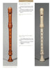 Two rare baroque recorders, one light brown and one white, stand upright side by side in "Four Centuries of Musical Instruments" by Schiffer Publishing, Ltd. Both feature finger holes, decorative rings, and detailed maker information above and below.