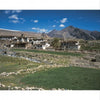 Experience the serene charm of Ladakh with Schiffer Publishing, Ltd.—rustic houses on rocky hillsides, lush green fields, and towering mountains beneath a brilliant blue sky.