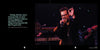 A man in black with sunglasses passionately sings on stage, making an OK gesture—a style favored by bikers. Musicians play under stage lights. Left text features "The Meaning of Life According to Bikers" by Schiffer Publishing, Ltd.
