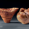 The Lindquist Legacy by Schiffer Publishing, Ltd. features two intricately carved wooden vessels—one fluted and conical with textured ridges, the other rounded with natural cracks—displayed against a dark background.