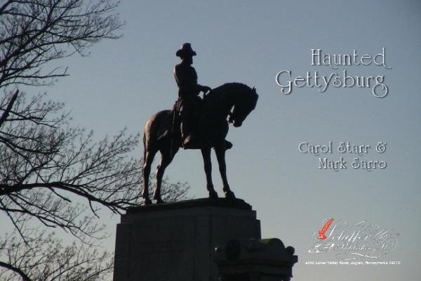 A statue of a man on horseback stands on a pedestal beneath a clear sky, bare trees to the left. The text "Haunted Gettysburg" invites you to explore Gettysburg ghosts. Product: Haunted Gettysburg by Schiffer Publishing, Ltd.