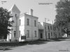 Black and white photo of the Old Clay County Jail—a two-story, white brick building with a tower and arched windows—featured in Schiffer Publishing, Ltd.'s "Women in White," known for its connections to northeast Florida ghost stories.