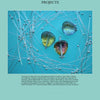 Three glass cabochons and a metal pin rest on a blue background with intersecting silver wires and beads, forming a geometric design featured in "Wire & Fused Jewelry" by Schiffer Publishing, Ltd.