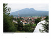 View of Santa Clara del Cobre, famed for hammered copper vessels featured in "Mexican Arts Series: Hammered Copper" by Schiffer Publishing, Ltd., with buildings, trees, a red and white radio tower, and a forested mountain under a cloudy sky.
