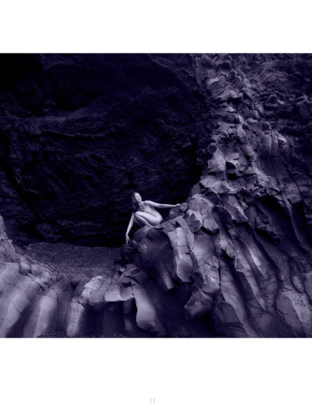A person sits on jagged rocks at a cave entrance, surrounded by textured stone and a purple hue—an image from "Bare Landscapes" by Schiffer Publishing, Ltd., evoking the dramatic mood typical of Iceland landscape photography.