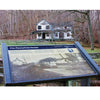 An informational sign about The Chesapeake and Ohio Canal by Schiffer Publishing, Ltd. stands in the foreground, while the old Pennyfield House appears among leafless trees in the historic canal's background.